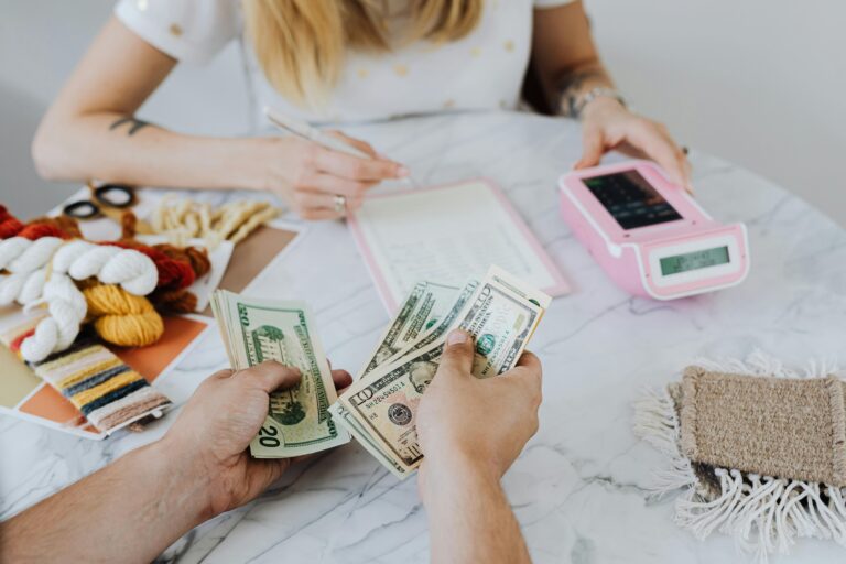 Two people handling cash and budgeting with a calculator and notebook at a table.